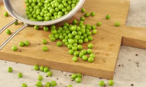 Frisch abgespülte Erbsen liegen auf einem Holzbrett. Bald werden sie gekocht und sind bereit für die nächste Mahlzeit.