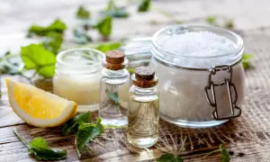Zutaten für kosmetik selber machen: Zitrone, ätherische Öle, Salz und Kräuter auf Holzuntergrund.