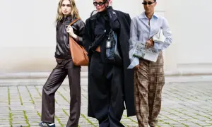 Drei Frauen in modischer Kleidung, die zeigt, was bedeutet nachhaltige Kleidung: Leder, Oversize-Schnitte und karierte Hosen.