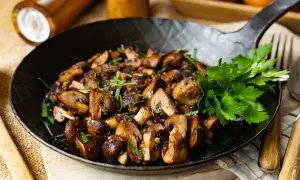 Gebratene Champignons mit Petersilie in einer Pfanne, perfekt zubereitet.