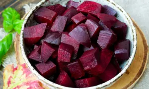 Schüssel mit gewürfelter roter Bete, die nach dem Kochen mit Essig glänzt. Ein Hauch von Herbst mit Blättern und Kräutern.