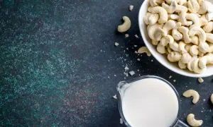 Cashewmilch selber machen ist einfach: Eine Schüssel voller Cashewkerne und ein Krug mit frischer Cashewmilch auf dunklem Untergrund.
