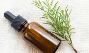 Braune Pipettenflasche neben frischem Rosmarin. Ideal für natürliche Pflege, besonders für rosmarin haare.