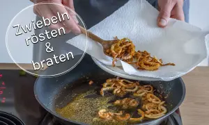 Goldbraune, knusprige gebratene Zwiebeln werden mit einem Holzlöffel aus einer Pfanne auf Küchenpapier gehoben.