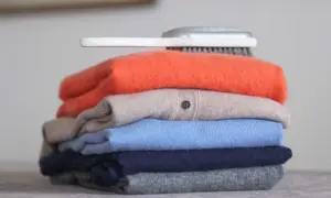Ein Stapel bunter Pullover, was ist Kaschmir? Weiche, luxuriöse Kleidung, die Pflege braucht. Ein Bürstchen liegt obenauf.