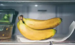 Ein Bund reifer Bananen liegt auf einem Küchentuch im Kühlschrank. So lassen sich Bananen lagern, um sie länger frisch zu halten.