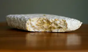 Ein Block Tempeh liegt auf einem Holztisch. Perfekt, um ihn für später einzufrieren.