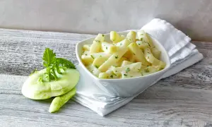 Schmackhafter Kohlrabi in cremiger Soße, daneben ein frischer Kohlrabi. Perfekt, wenn man wissen will, wie lange muss Kohlrabi kochen.