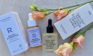Zwei Hautpflegeprodukte mit Bakuchiol Öl, umgeben von zarten Blüten. Die Produkte versprechen eine sanfte Wirkung für straffere Haut.