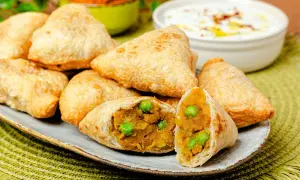 Goldbraune Samosas mit Erbsen und Kartoffelfüllung, perfekt für ein leckeres samosa rezept. Dazu ein Dip.