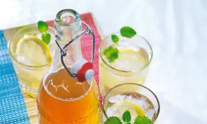 Erfrischender zitronenmelisse sirup in einer Bügelflasche, serviert mit Eis, Zitronenscheiben und Minze in Gläsern.