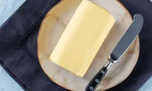 Ein Block Butter auf einem Teller mit einem Messer daneben. Die Frage, wie lange ist Butter haltbar, beschäftigt viele.