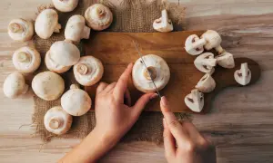 Hände schneiden frische Champignons für einen gesunden Snack. Roh essen ist eine tolle Option!