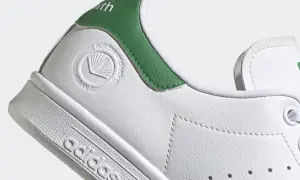 Detailaufnahme eines weißen Adidas Stan Smith Schuhs mit grünen Akzenten. Das vegane Siegel ist gut sichtbar. Perfekt für leichte, vegane Sommerschuhe.