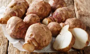 Frische Topinamburknollen auf Holzuntergrund, bereit für die Lagerung. Tipps zur Topinambur haltbar machen.