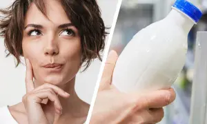 Frau denkt nach, ob kann hafermilch schlecht werden. Eine Hand hält eine Flasche mit weißer Flüssigkeit.