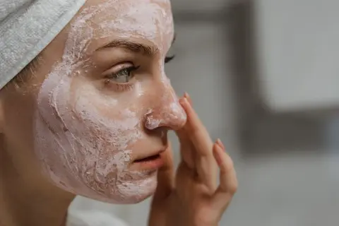 Frau mit Gesichtsmaske, die ihre Haut mit probiotischer Hautpflege pflegt.