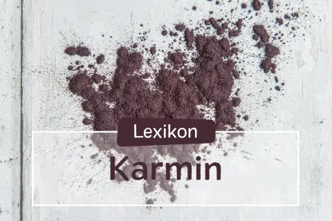 Ein Haufen echtes Karmin-Pulver, das auf einer hellen Oberfläche verstreut ist. Der Text "Lexikon Karmin" ist überlagert.