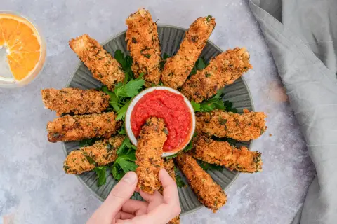 Knusprig paniertes Tofu, goldbraun gebacken, wird mit einer Schale Tomatensoße serviert. Ein perfekter Snack für alle, die Tofu panieren lieben.