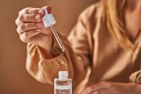 Eine Hand hält eine Pipette mit Glycerin, das in eine kleine Flasche tropft. Die Glycerin Verwendung ist ideal für die Hautpflege.