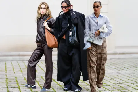 Drei Frauen in modischer Kleidung, die zeigt, was bedeutet nachhaltige Kleidung: Leder, Oversize-Schnitte und karierte Hosen.