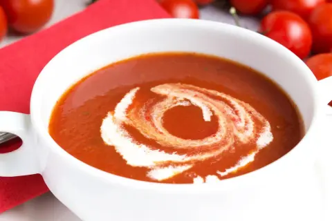 Eine cremige Tomatensuppe, perfekt für ein Tomatensuppe Rezept mit frischen Tomaten. Mit einem Swirl aus Sahne verziert.