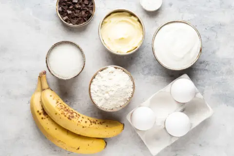 Reife Bananen, Mehl, Zucker, Butter, Eier, Schokolade und Joghurt – alles bereit, um die Bananen zu verwerten und etwas Leckeres zu backen.
