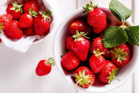 Frische, rote Erdbeeren in einer Schale und einem Körbchen, bereit, um sie frisch zu halten.