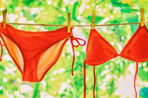 Roter Bikini trocknet an der Leine. Nach dem **Bikini waschen** duftet er frisch nach Sommer.