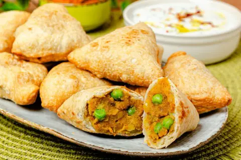 Goldbraune Samosas mit Erbsen und Kartoffelfüllung, perfekt für ein leckeres samosa rezept. Dazu ein Dip.