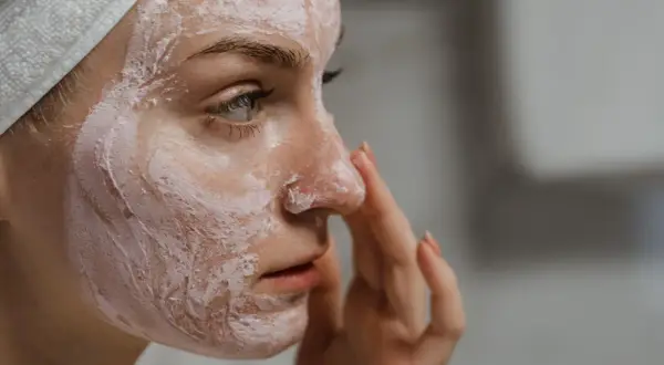 Frau mit Gesichtsmaske, die ihre Haut mit probiotischer Hautpflege pflegt.