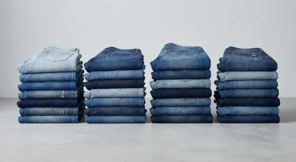 Stapel von Jeanshosen in verschiedenen Blautönen. Sie zeigen, aus was Jeans bestehen: robustem Denim-Stoff.