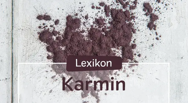 Ein Haufen echtes Karmin-Pulver, das auf einer hellen Oberfläche verstreut ist. Der Text "Lexikon Karmin" ist überlagert.