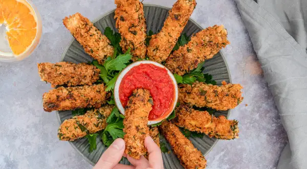 Knusprig paniertes Tofu, goldbraun gebacken, wird mit einer Schale Tomatensoße serviert. Ein perfekter Snack für alle, die Tofu panieren lieben.