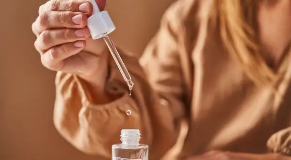 Eine Hand hält eine Pipette mit Glycerin, das in eine kleine Flasche tropft. Die Glycerin Verwendung ist ideal für die Hautpflege.