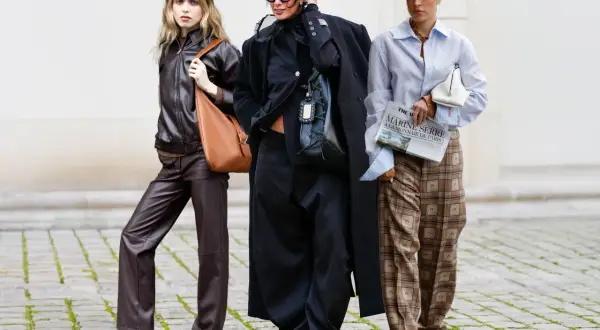 Drei Frauen in modischer Kleidung, die zeigt, was bedeutet nachhaltige Kleidung: Leder, Oversize-Schnitte und karierte Hosen.