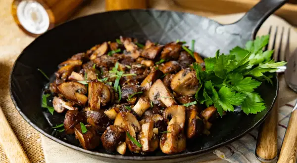 Gebratene Champignons mit Petersilie in einer Pfanne, perfekt zubereitet.