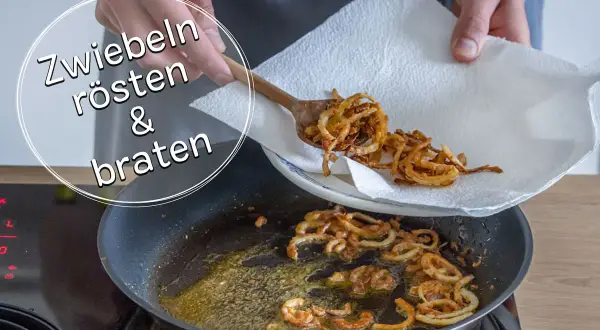 Goldbraune, knusprige gebratene Zwiebeln werden mit einem Holzlöffel aus einer Pfanne auf Küchenpapier gehoben.