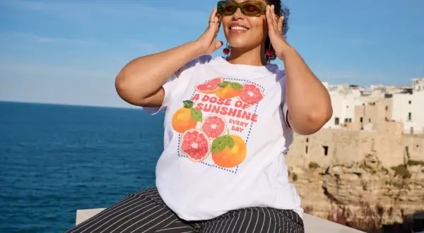 Frau mit Zitrusfrüchten-T-Shirt und gestreiften Hosen, perfekt für eine **capsule wardrobe sommer**.