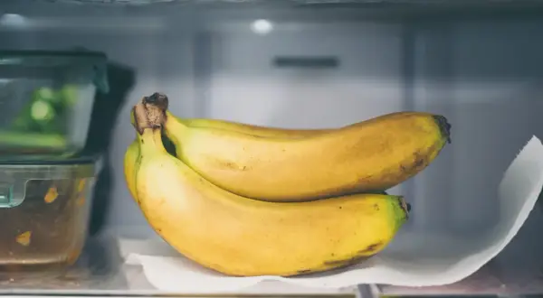 Ein Bund reifer Bananen liegt auf einem Küchentuch im Kühlschrank. So lassen sich Bananen lagern, um sie länger frisch zu halten.