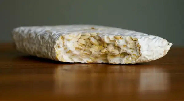 Ein Block Tempeh liegt auf einem Holztisch. Perfekt, um ihn für später einzufrieren.