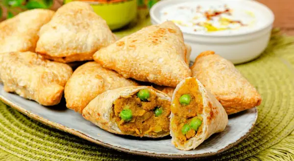 Goldbraune Samosas mit Erbsen und Kartoffelfüllung, perfekt für ein leckeres samosa rezept. Dazu ein Dip.