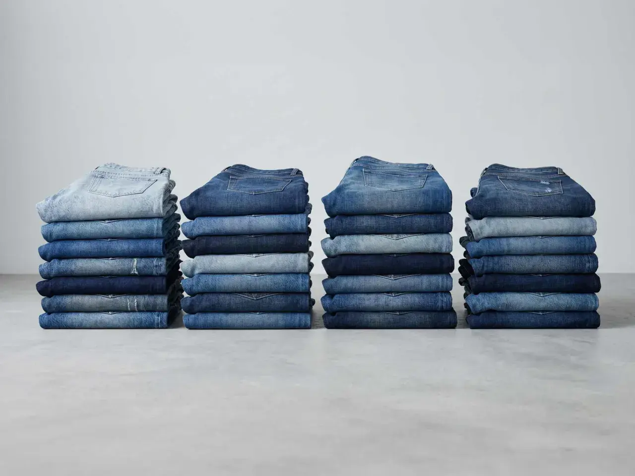 Stapel von Jeanshosen in verschiedenen Blautönen. Sie zeigen, aus was Jeans bestehen: robustem Denim-Stoff.