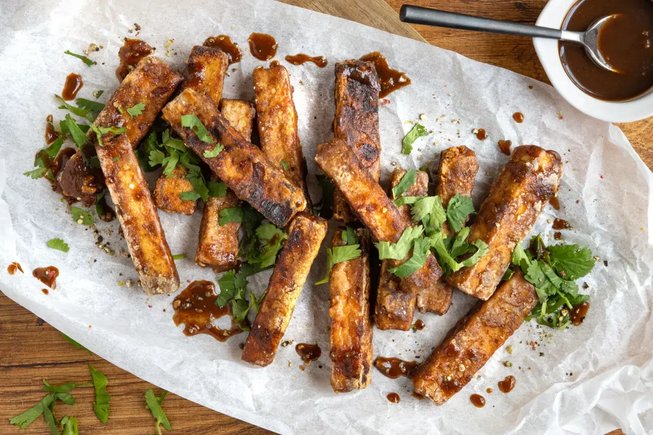 Marinierter Tofu, knusprig gebraten und mit einer dunklen Sauce beträufelt, garniert mit frischem Koriander. Perfekt zum **Tofu marinieren** und Genießen.