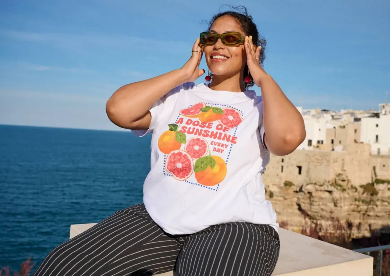 Frau mit Zitrusfrüchten-T-Shirt und gestreiften Hosen, perfekt für eine **capsule wardrobe sommer**.