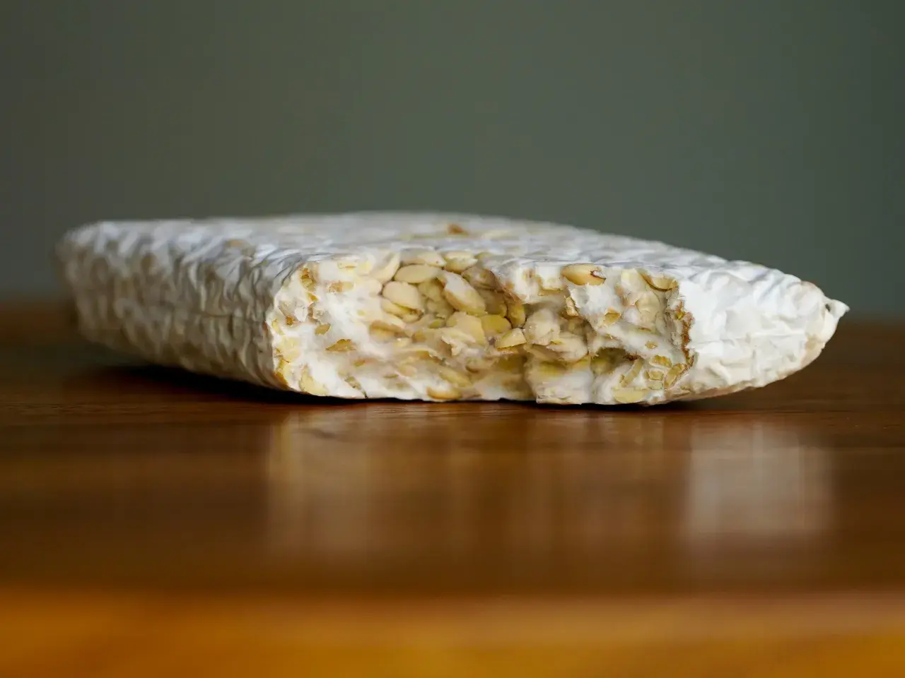 Ein Block Tempeh liegt auf einem Holztisch. Perfekt, um ihn für später einzufrieren.