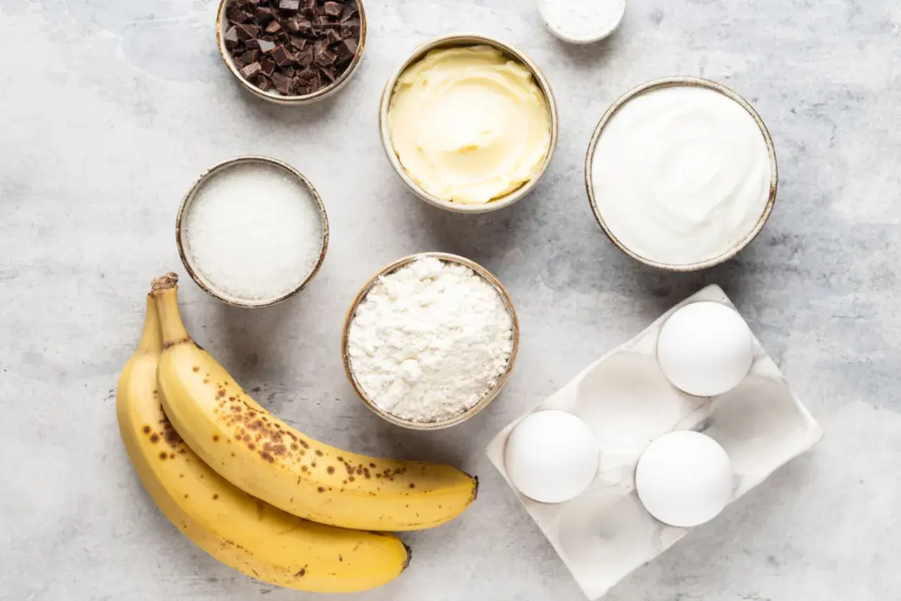 Reife Bananen, Mehl, Zucker, Butter, Eier, Schokolade und Joghurt – alles bereit, um die Bananen zu verwerten und etwas Leckeres zu backen.
