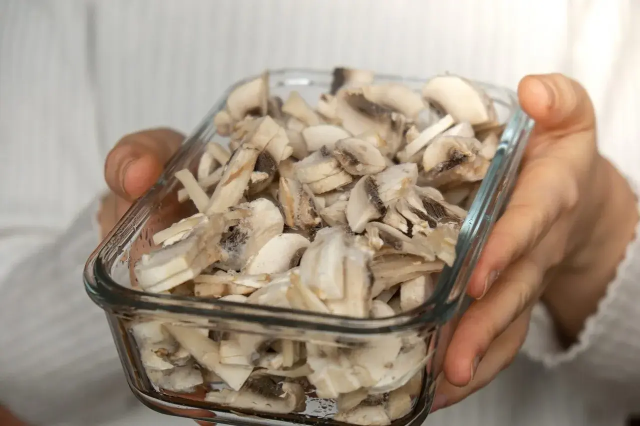 Gefrorene Champignons in einem Glasbehälter, bereit zum Einfrieren.