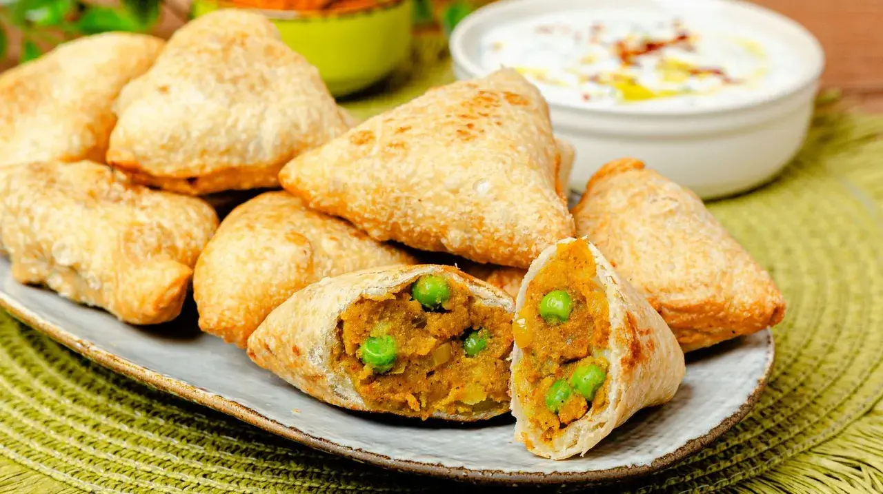Goldbraune Samosas mit Erbsen und Kartoffelfüllung, perfekt für ein leckeres samosa rezept. Dazu ein Dip.