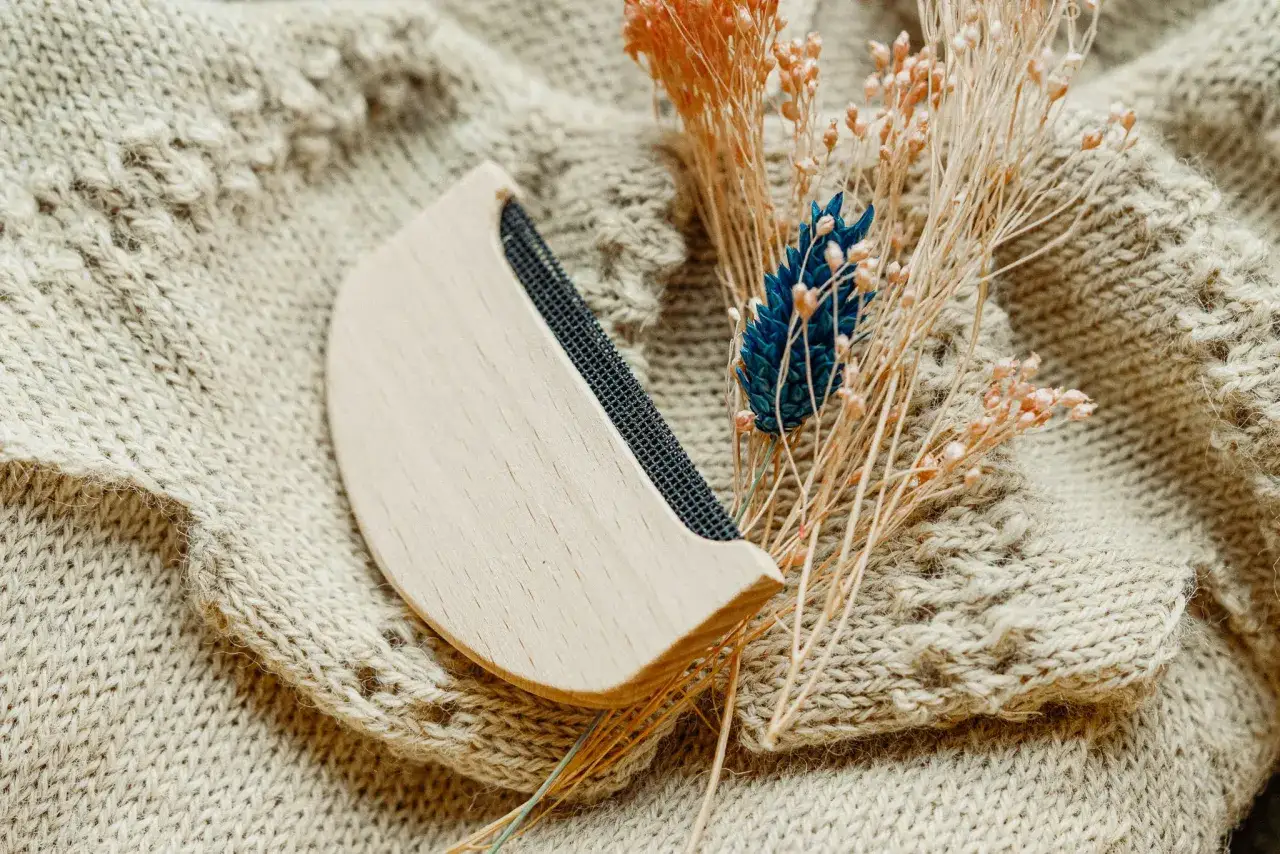 Ein Wollkamm auf einem Strickpullover. Was ist Kaschmir? Diese feine Wolle wird aus dem Unterfell von Kaschmirziegen gewonnen und ist bekannt f&uuml;r ihre Weichheit und W&auml;rme.